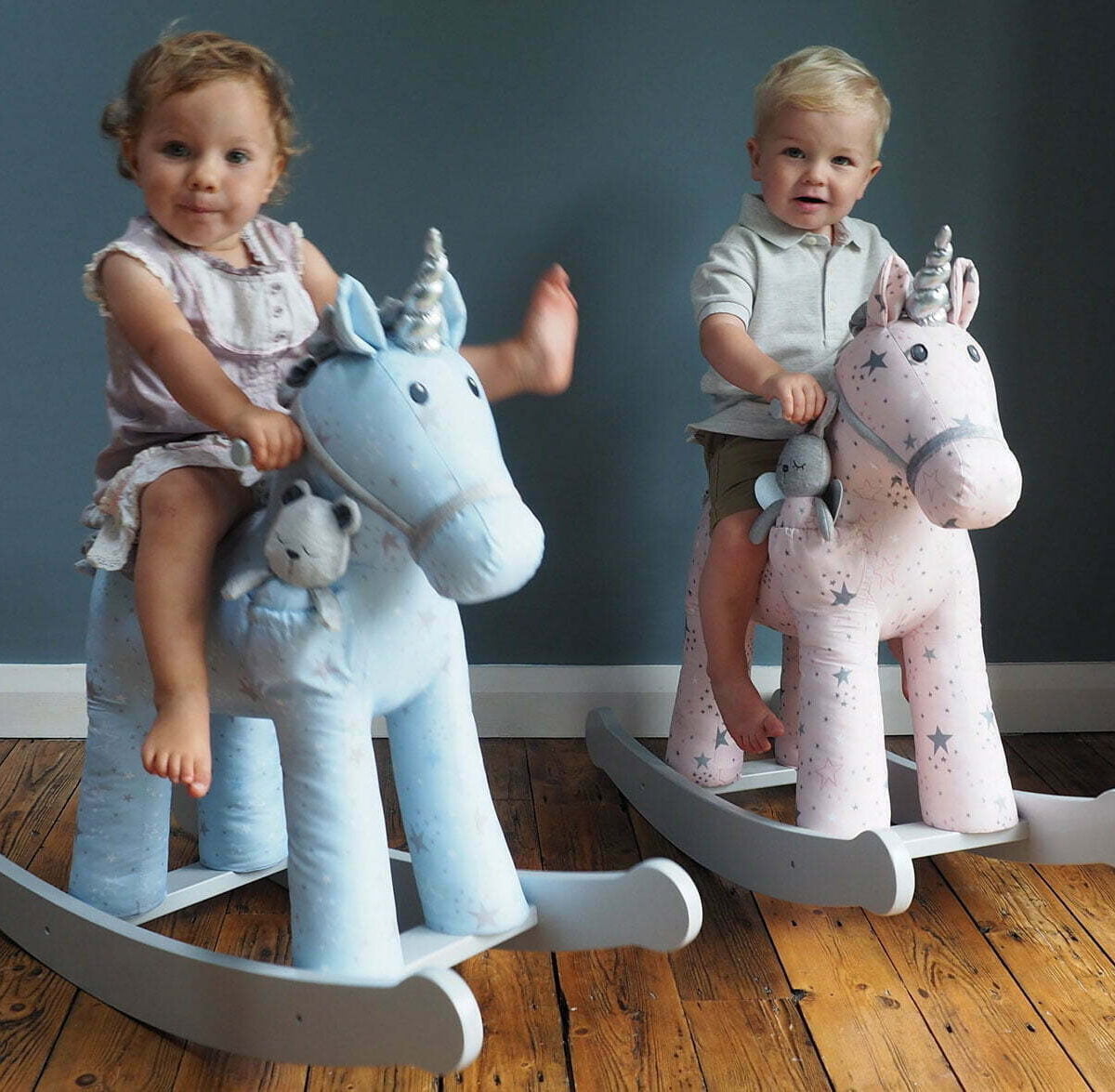 Girl riding a blue Moonbeam & Rae Rocking Unicorn and boy riding a pink Celeste & Fae Rocking Unicorn