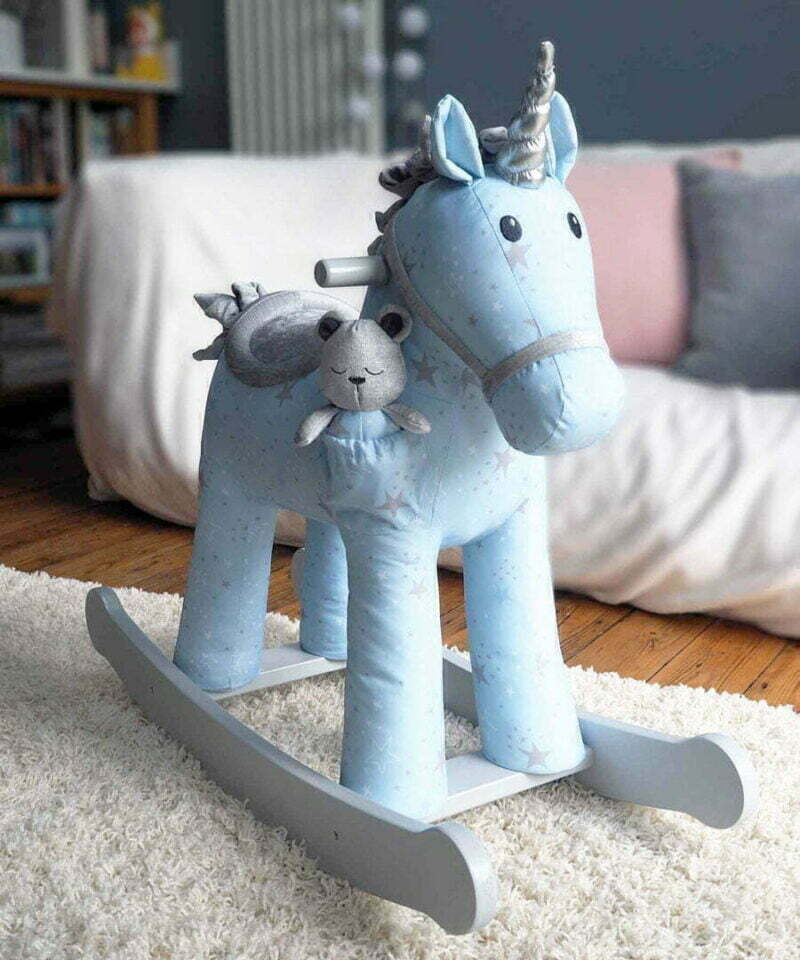 blue Moonbeam & Rae Rocking Unicorn standing in front of a cream sofa