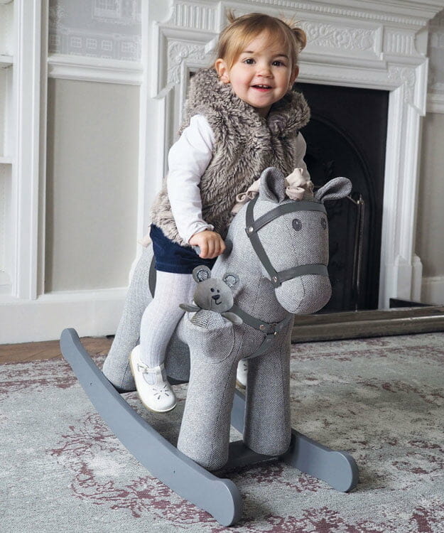 Girl rocking on a Stirling & Mac Rocking Horse in front of fireplace