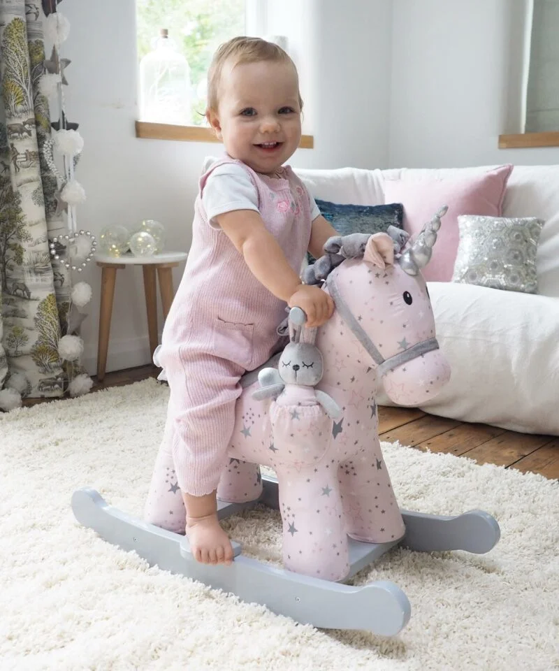 Girl riding a Celeste & Fae Rocking Unicorn standing on a cream rug