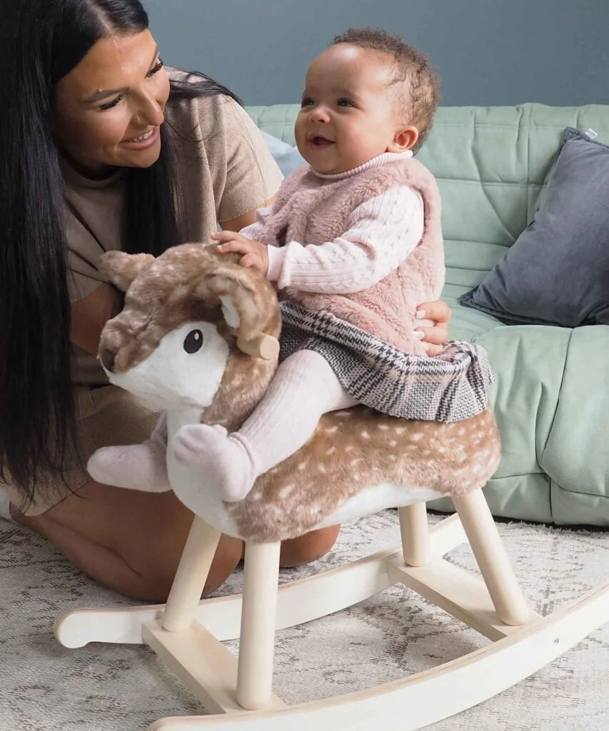 Mum supporting baby girl sitting on baby rocking Deer