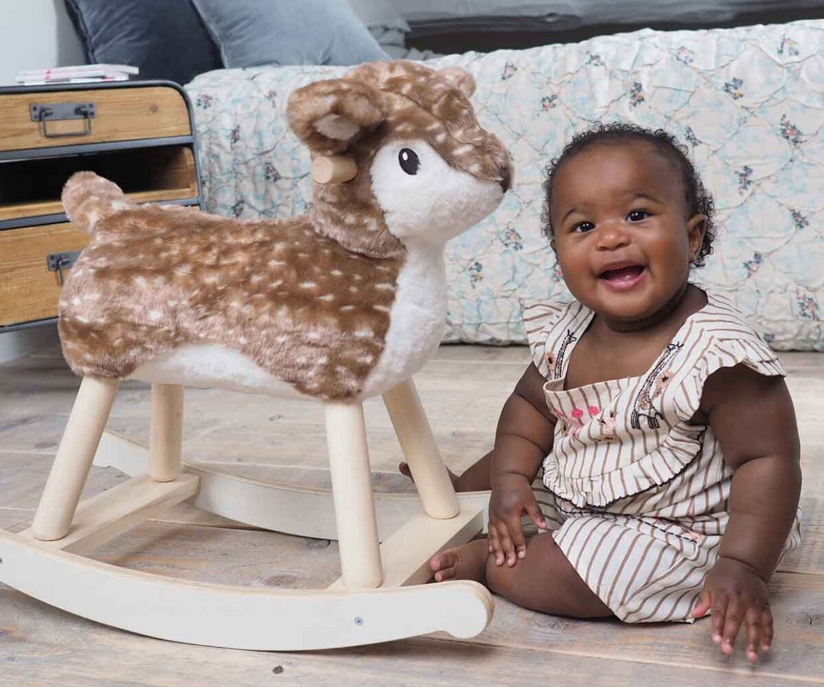 Infant girl sat next to Willow Rocking Deer on wooden floor