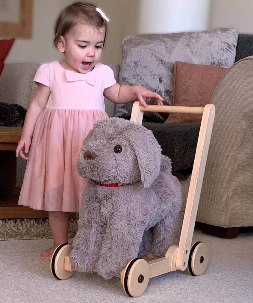 Little girl in pink dress pushes Bailey Dog Baby Walker with sturdy wooden frame