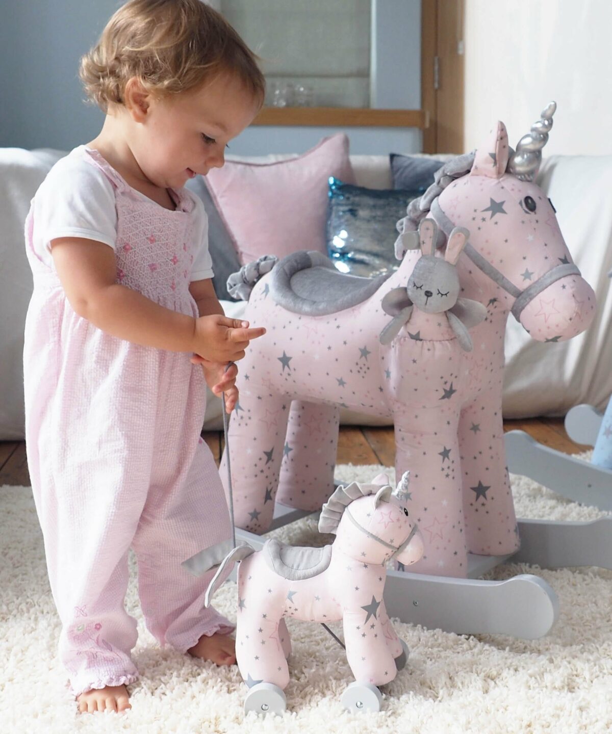 Toddler girl playing with Celeste Rocking Unicorn and Celeste Pull Along unicorn toy 