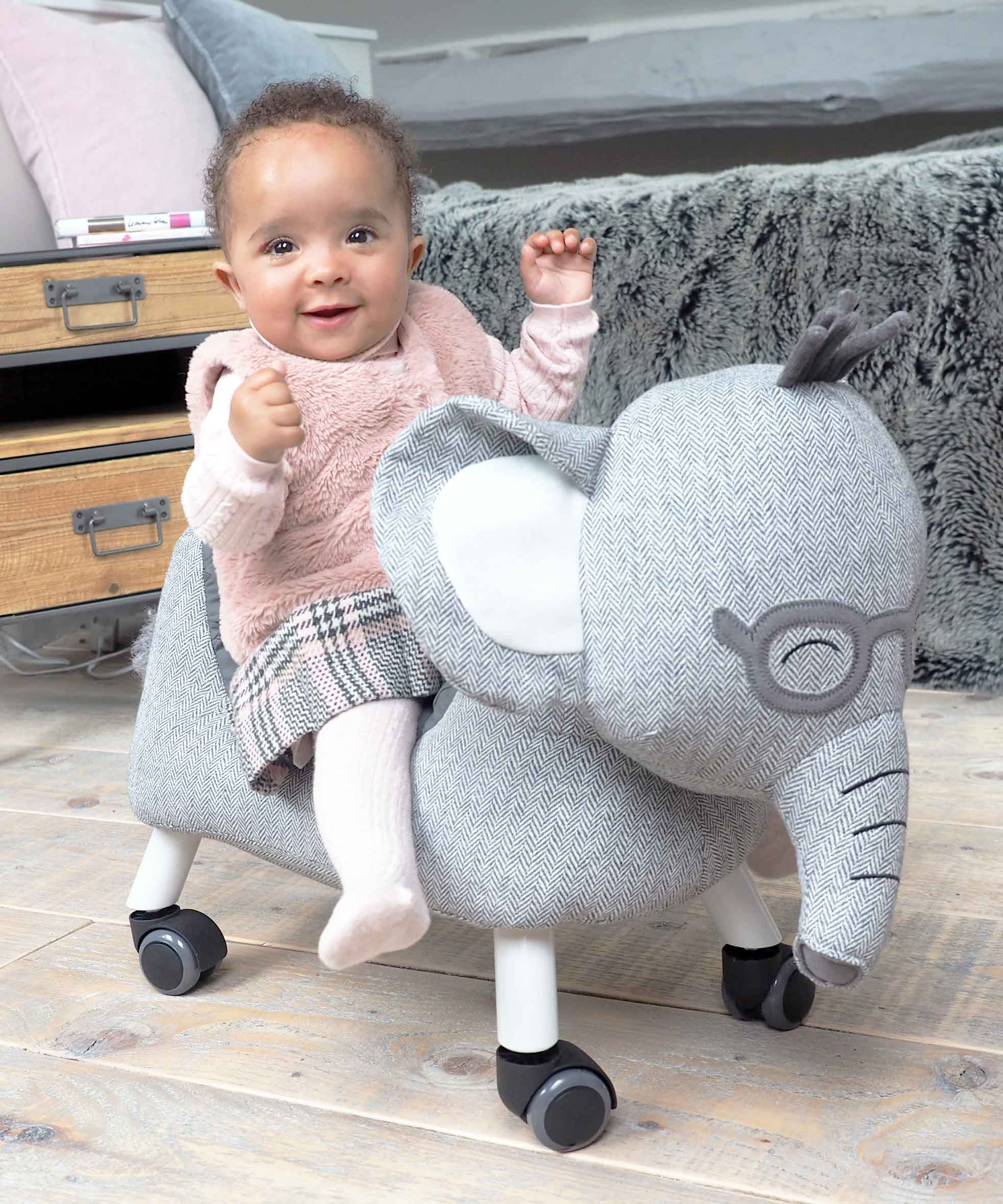 Little girl riding Cuthbert Elephant Ride On Toy with floppy ears