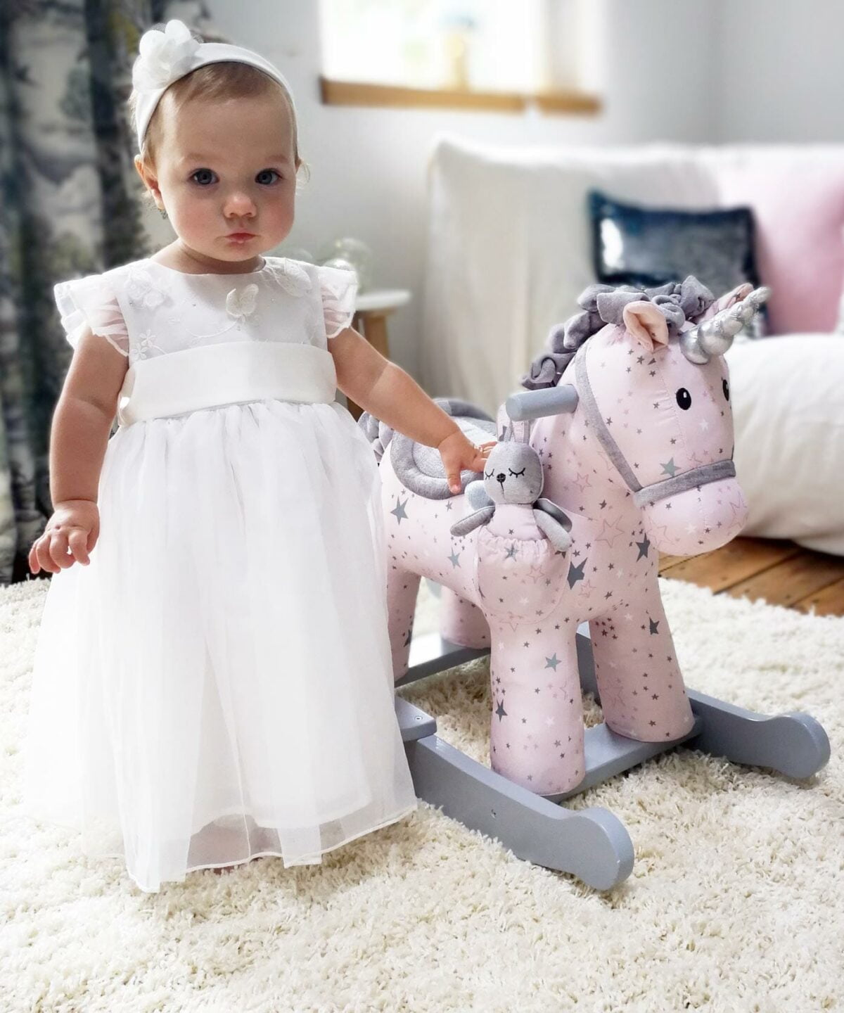 Girl standing next to Celeste & Fae Rocking Unicorn with pink star print fabric