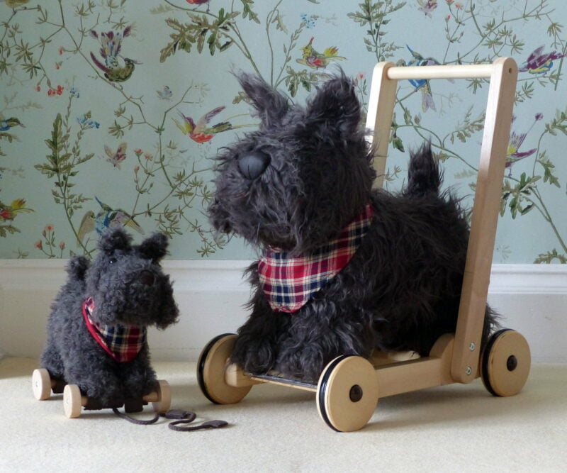 Scottie Dog Baby Walker and Scottie Dog Pull Along Toy standing in front of green patterned wallpaper