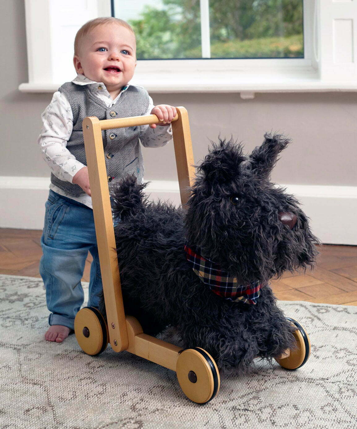 Little boy wearing a waistcoat pushes Scottie Dog Baby Walker