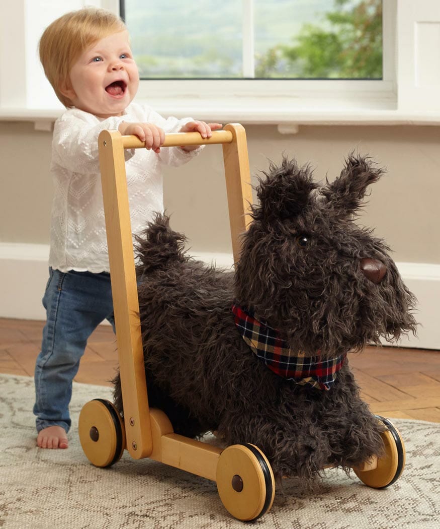 Little girl merrily pushes Scottie Dog Baby Walker with wooden wheels