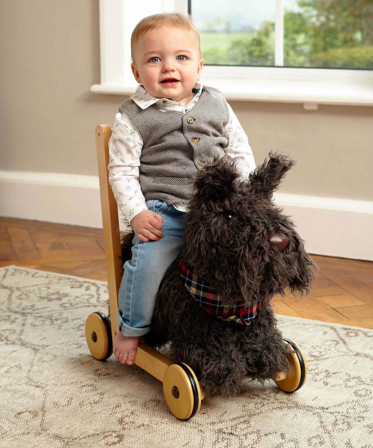 Little boy riding on Scottie Dog Baby Walker on a cream rug