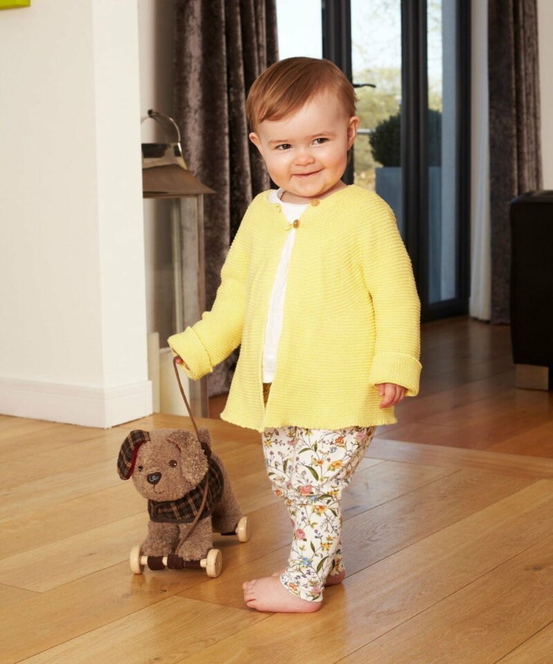 Toddler wearing yellow cardigan taking Percy Pup Pull Along Toy for a walk