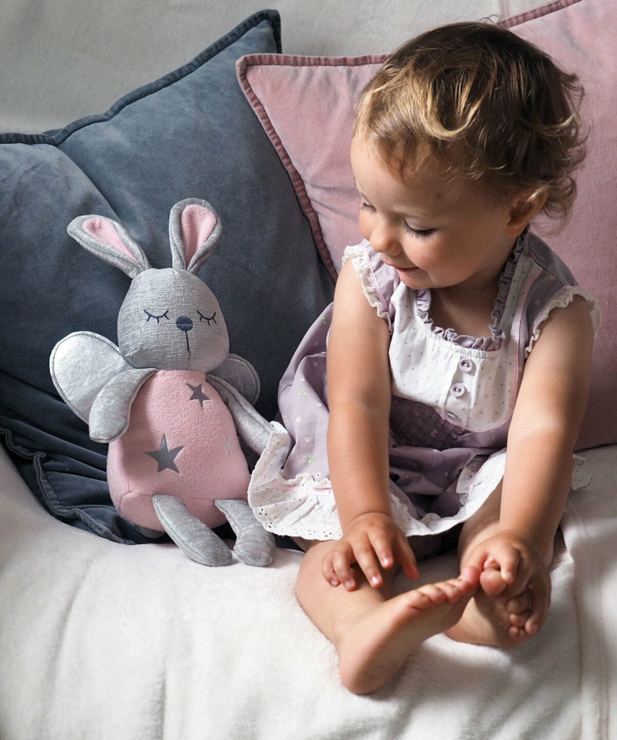Toddler girl sits alongside pink Fae Fairy Hug Toy