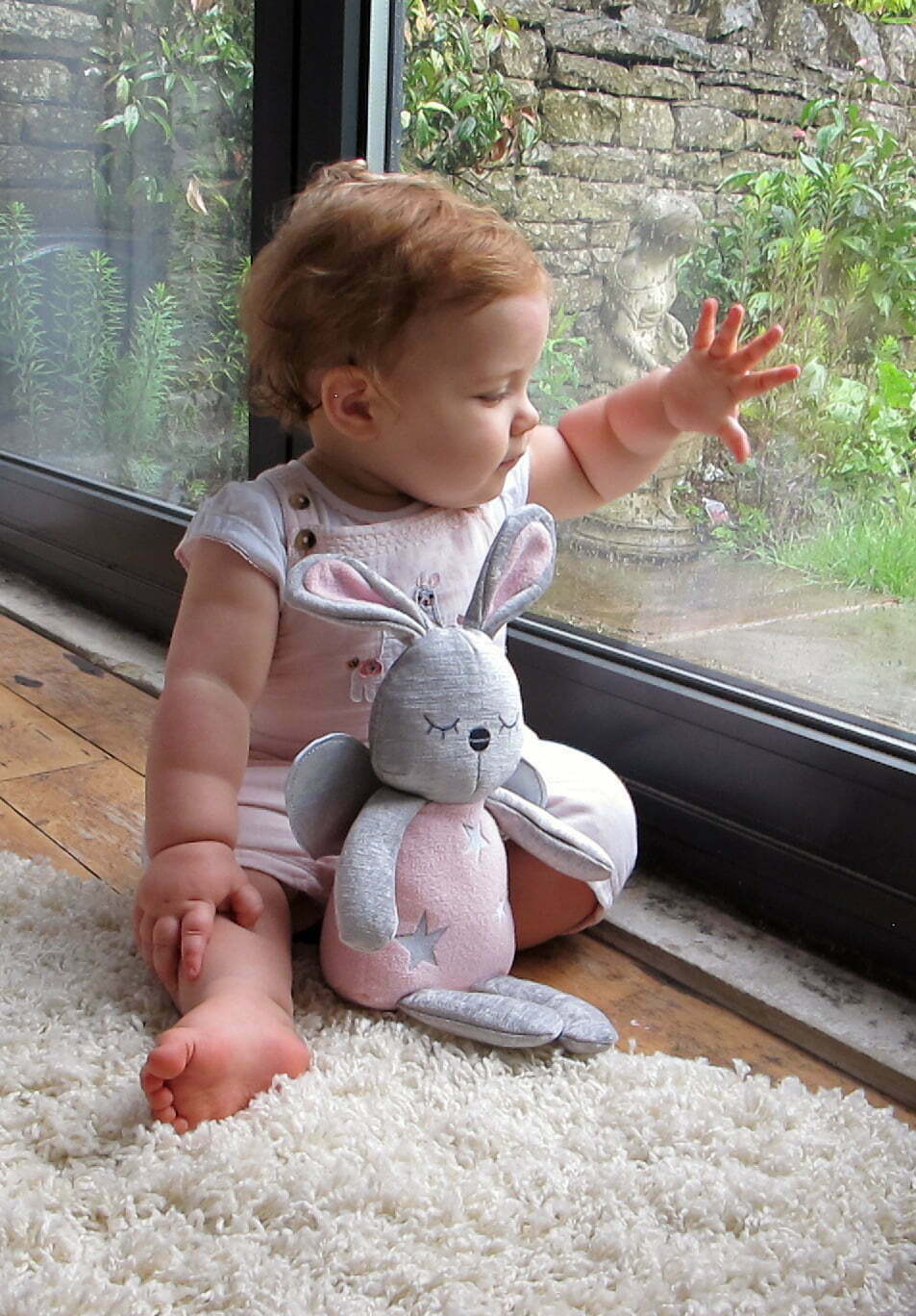 Little girl with Fae Fairy Hug Toy looking out the window 