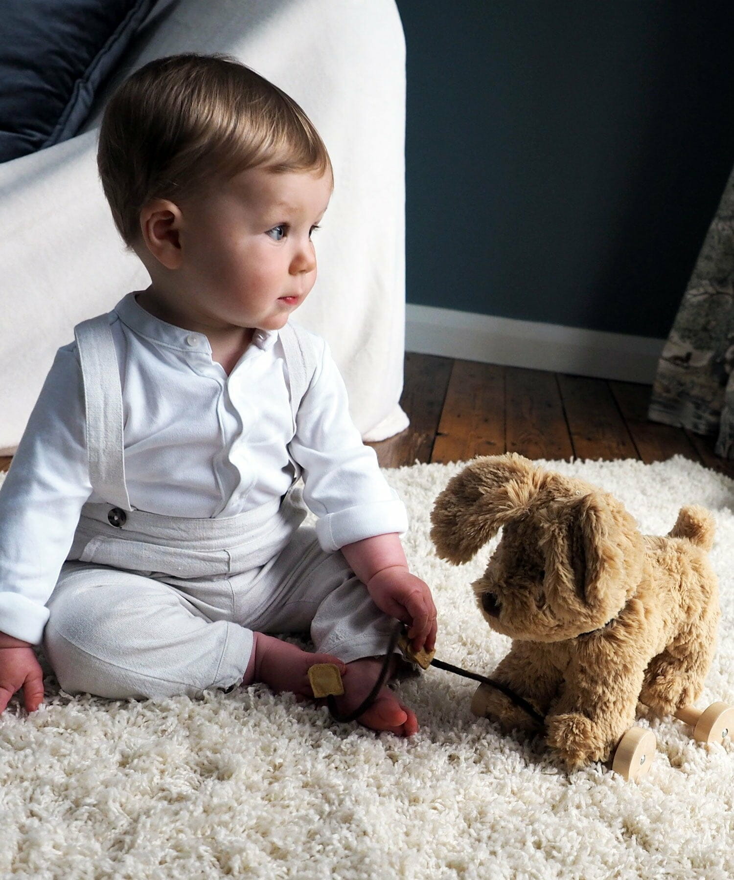 Baby Boy playing with Dexter Dog Pull Along Toy on a fluffy cream rug