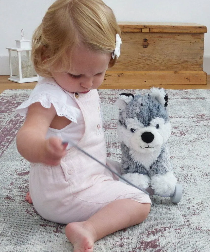 Little girl playing with Mishka Huskie Dog Pull Along Toy with removable wooden wheels