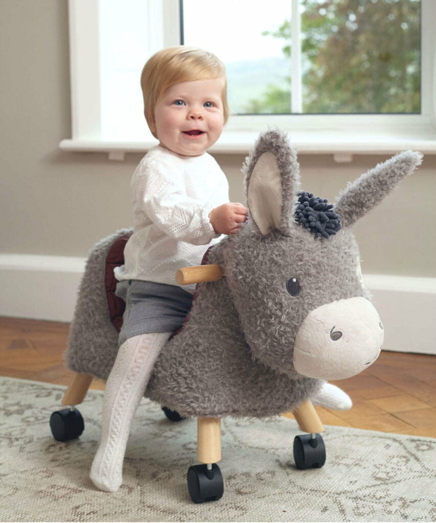 Little girl riding Bojangles Donkey Ride On Toy with supportive seat