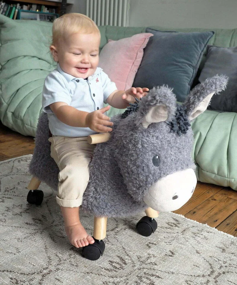 Little boy riding Bojangles Donkey Ride On Toy for toddlers with multidirectional castor wheels