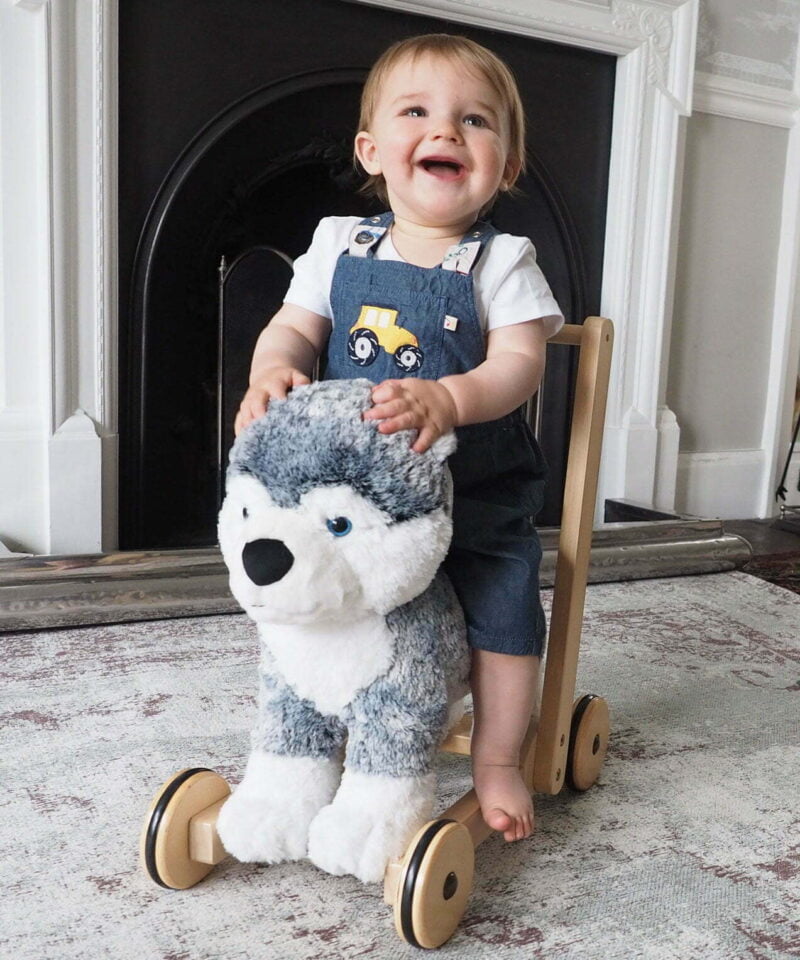 Little boy riding on Mishka Dog Baby Walker with sturdy wooden frame