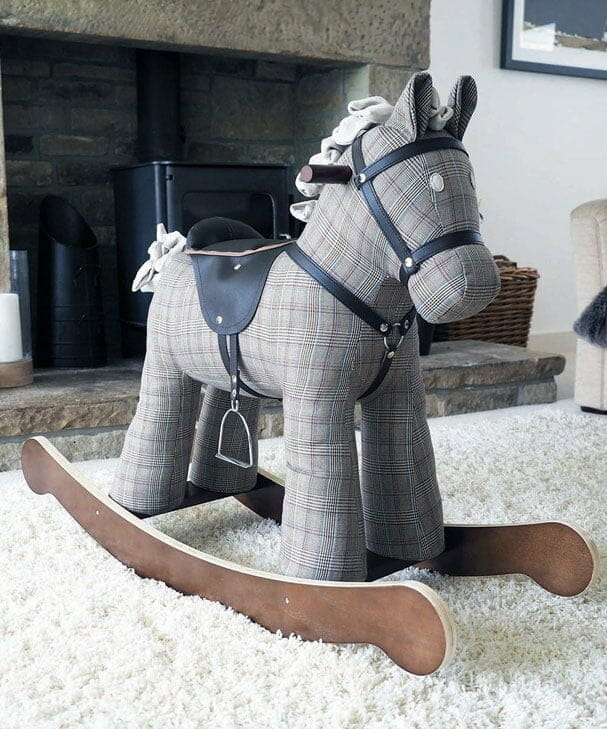 1st birthday gift classic rocking horse - Jasper - sits on a cream rug in front of a fireplace.