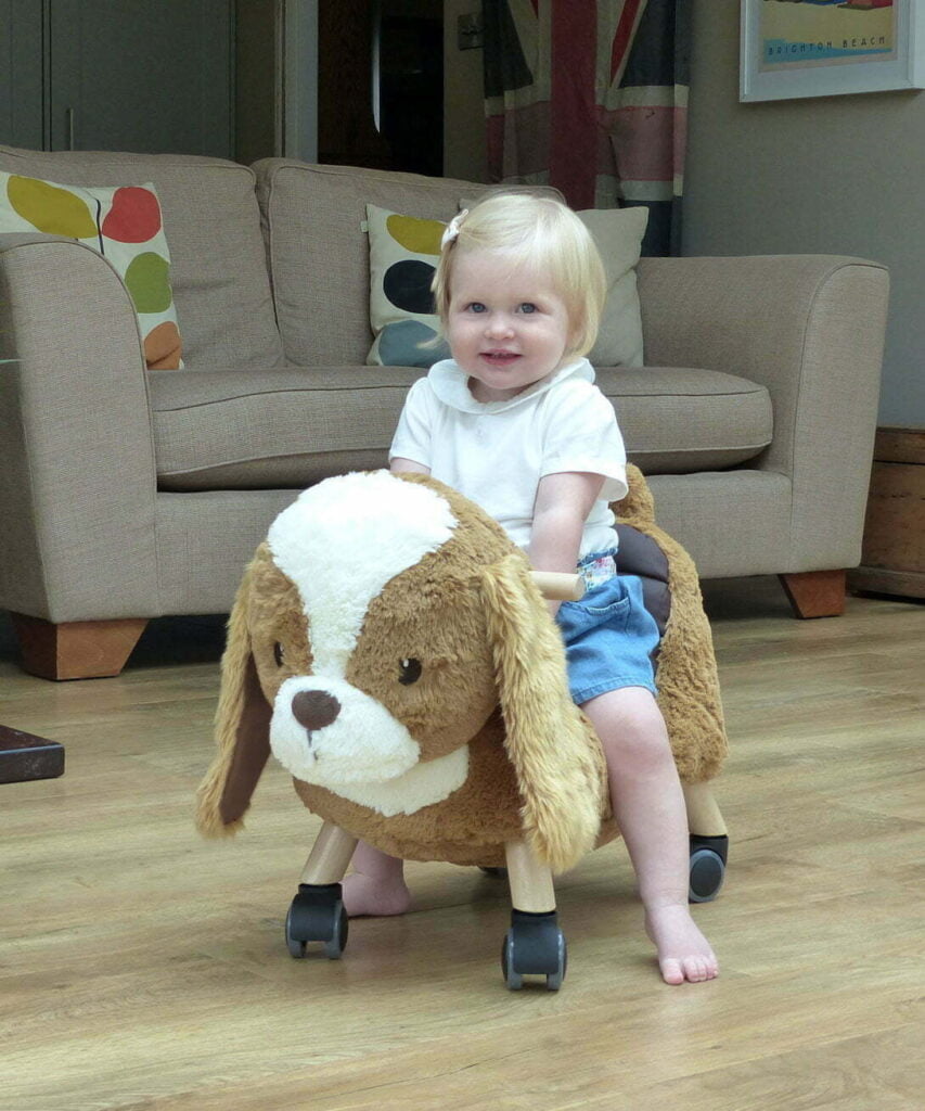 Little girl riding on Peanut Pup Animal Ride On Toy