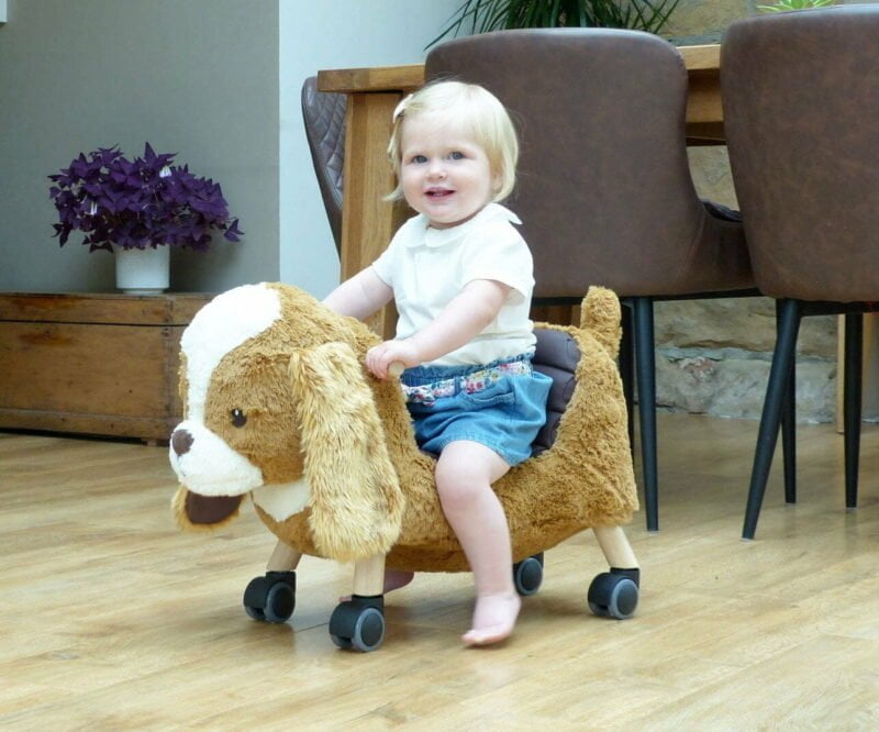 Toddler girl in Demin shorts scooting on Peanut Pup Animal Ride On Toy