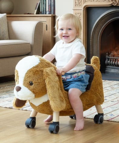 Young Girl smiling sat on Peanut Pup Animal Ride On Toys for toddlers 