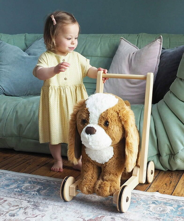 Toddler girl in yellow dress holding Peanut Pup push along dog Walker