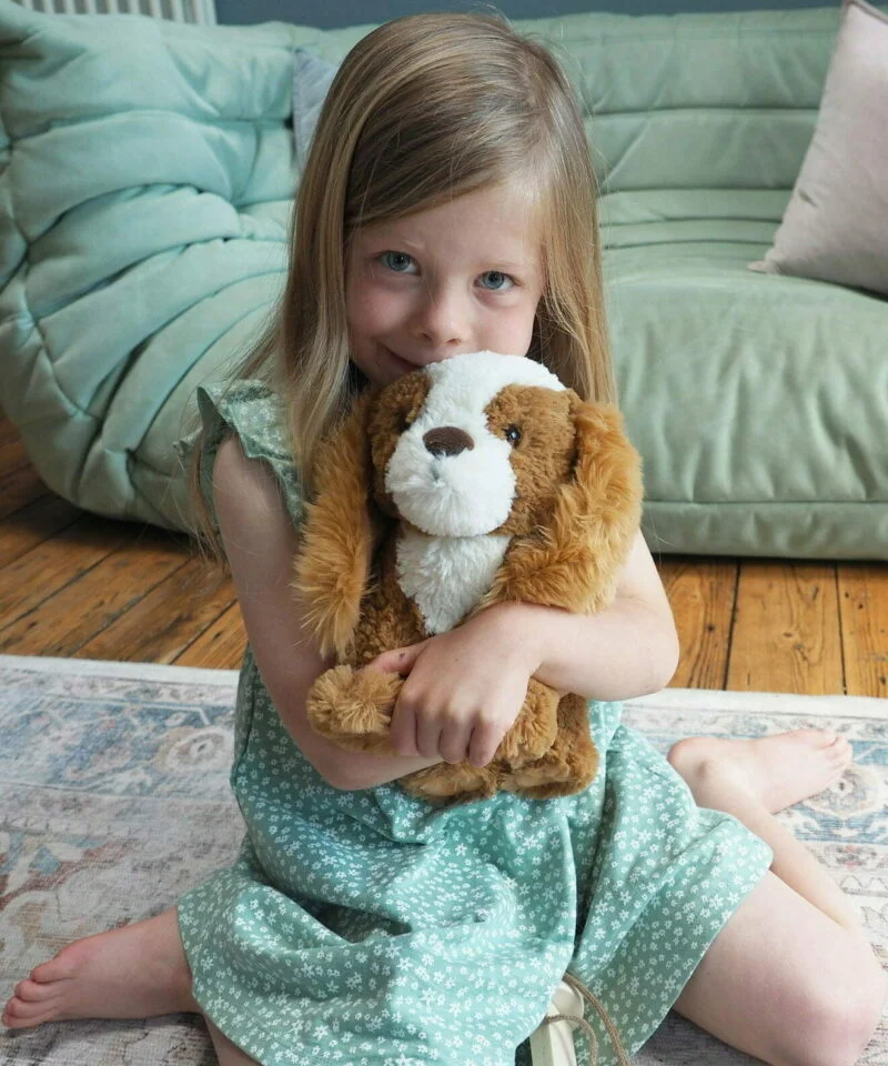 Girl cuddling peanut puppy dog toy 
