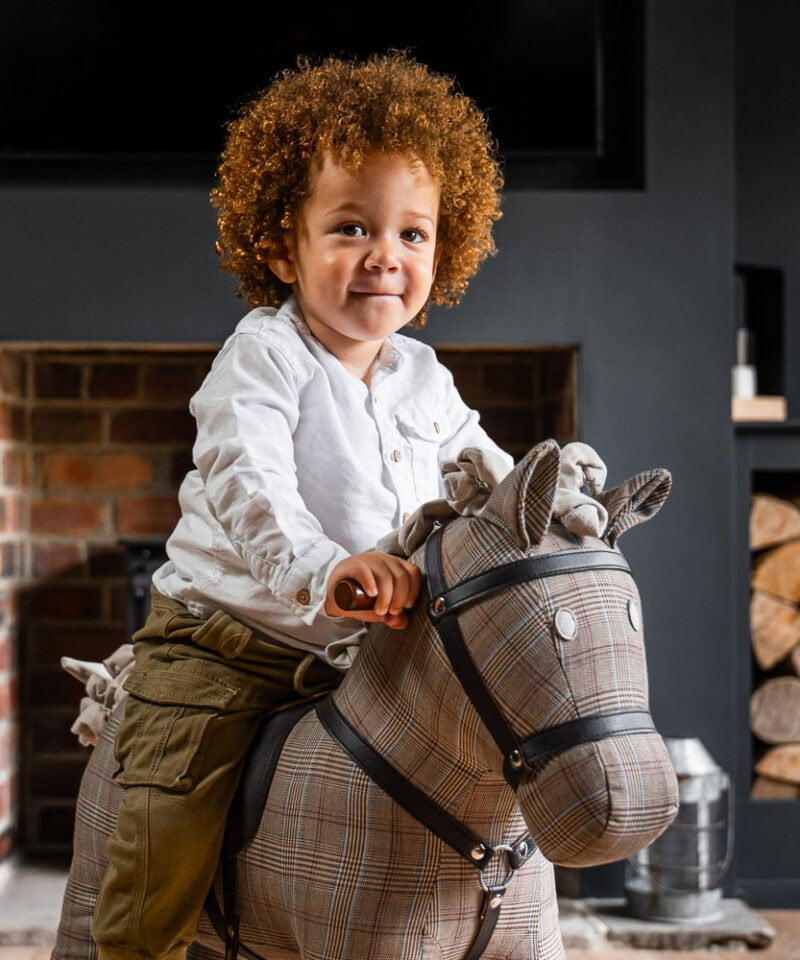 toddler boy smiling whilst riding jasper rocking horse