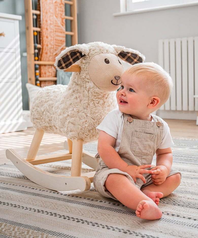 Little boy sat on floor in nursery next to lambert rocking sheep 