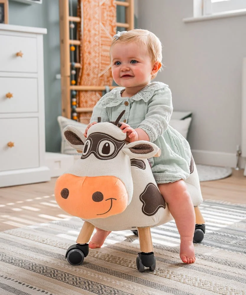1 year old girl on moobert cow ride on in nursery room 