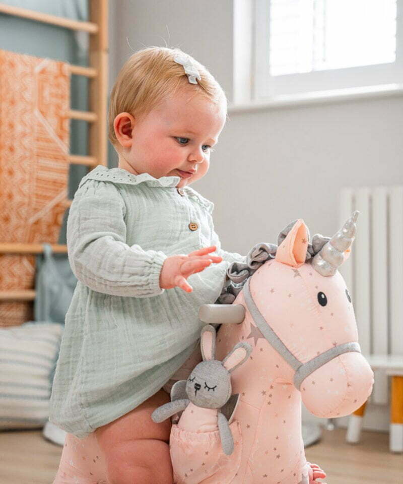 little girl playing with unicorn in playroom 