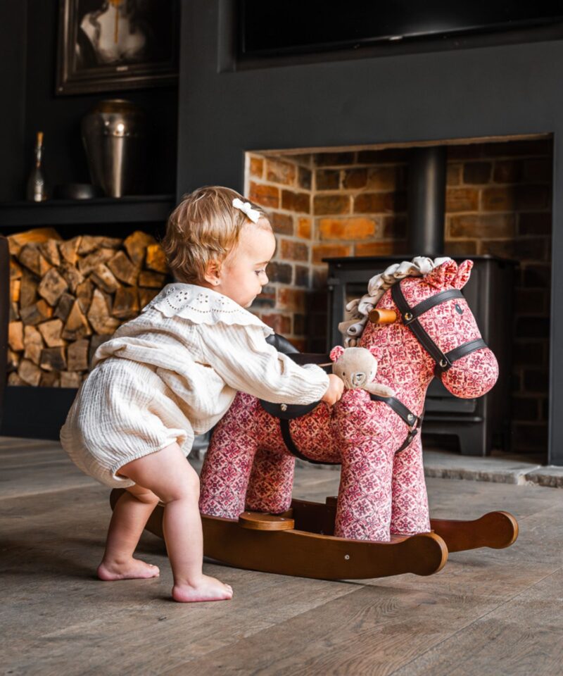 little girl playing with rockinghorse in living room 