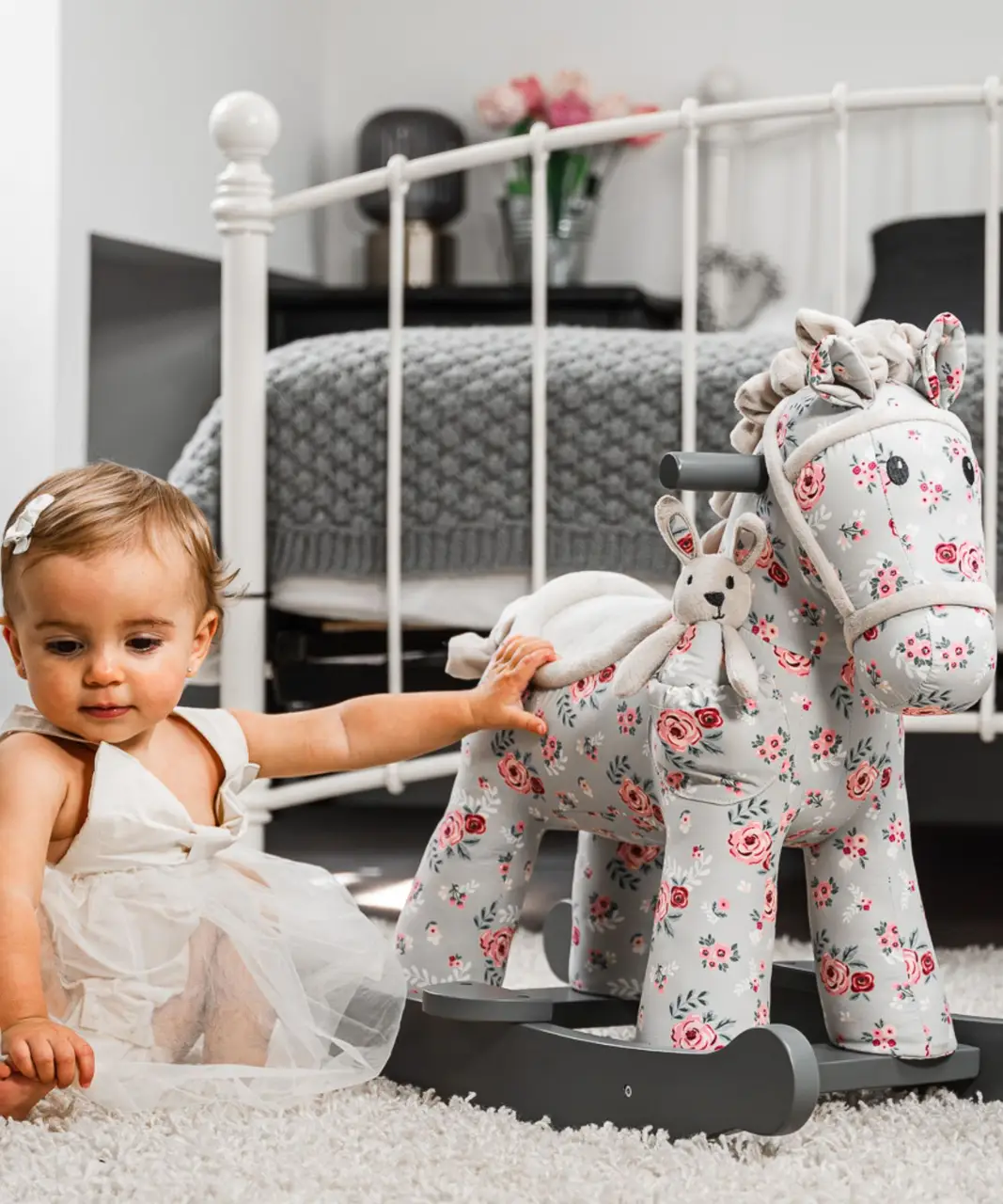 little girl in nursery room sat with floral printed horse