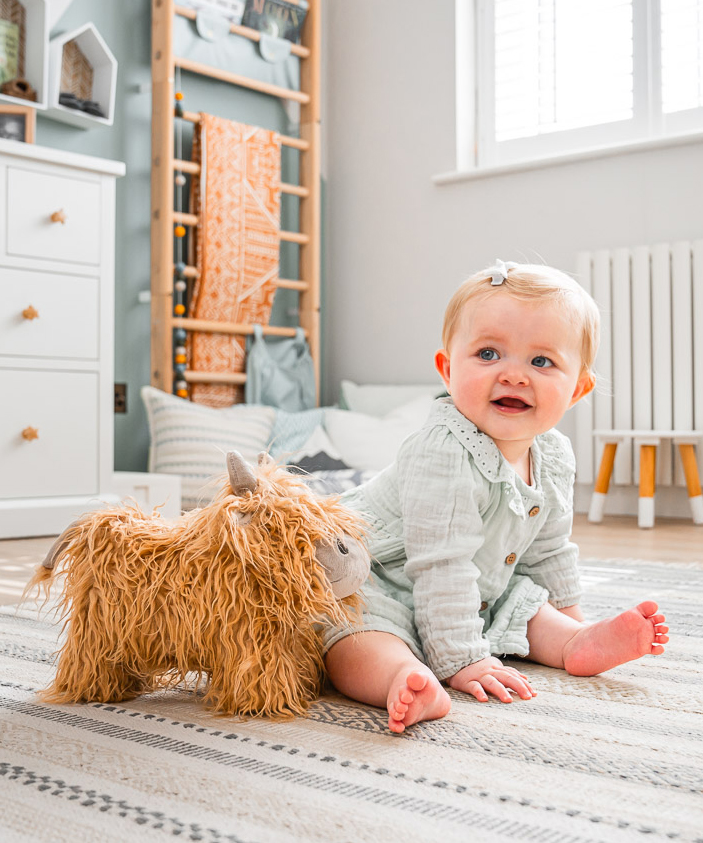 Toddler playing with highland cow teddy toy