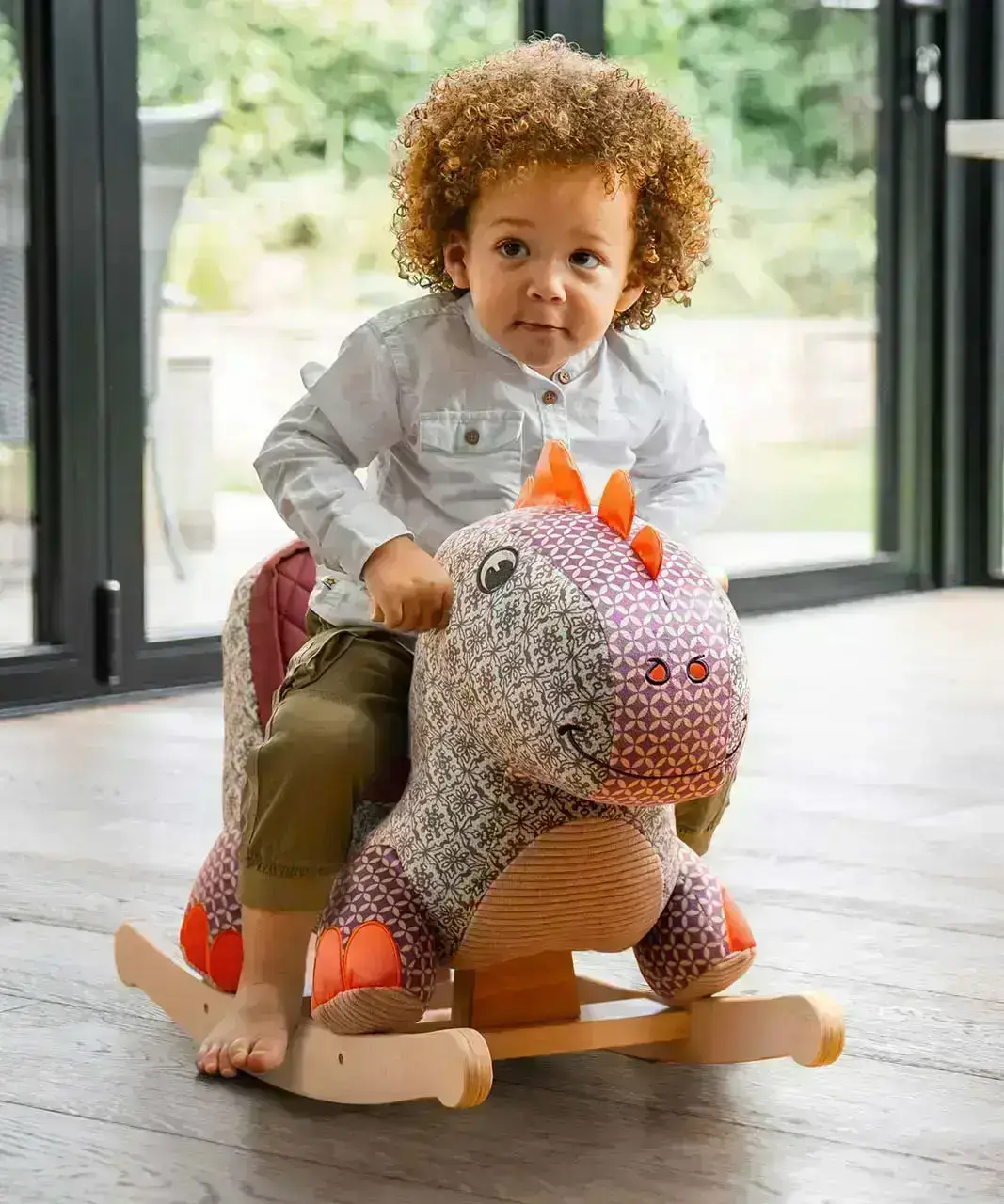 Little boy sitting on a dinosaur rocker